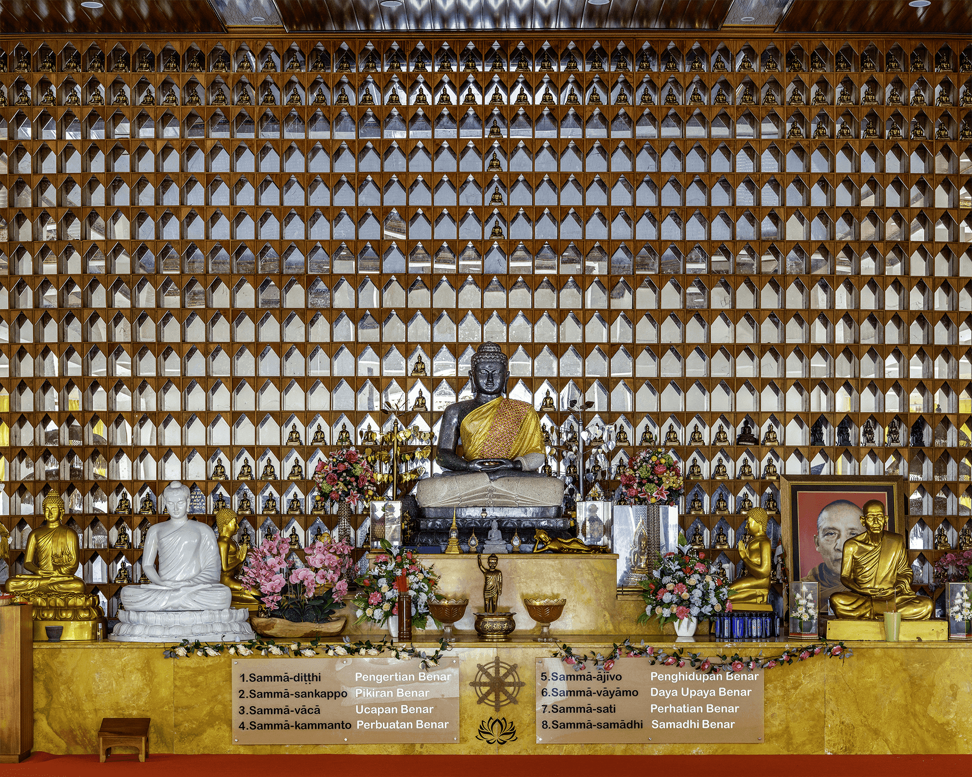 Patung Buddha duduk di Pondok Meditasi Bhante Win, dikelilingi oleh patung-patung kecil dan artefak Buddhis lainnya.