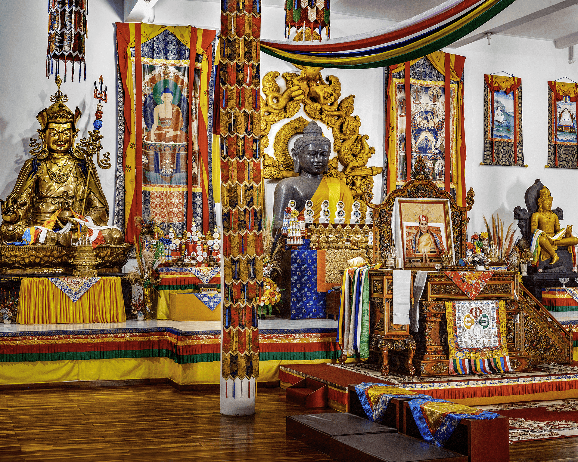 Patung-patung Buddha di Vihara Graha Padmasambhava, dikelilingi oleh dekorasi dan artefak Buddhis.